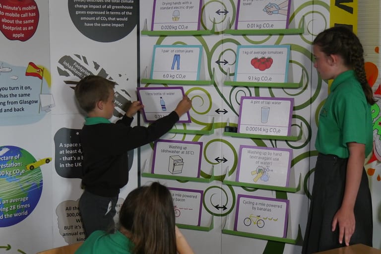 Two school children playing with the big carbon footprint game.